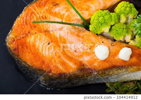 Cooked dish of tasty fried salmon with broccoli served on plate Cooked dish of tasty fried salmon with broccoli served on plate 104414912