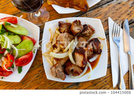 Grilled pork shashlik with fresh onion and vegetable salad 104415008