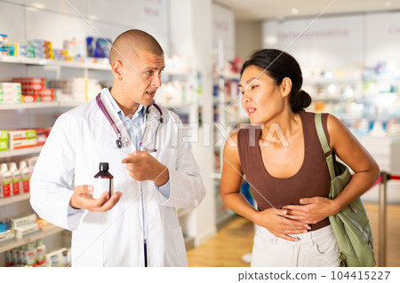 Pharmacist offering medicine for sore belly to patient at pharmacy closeup 104415227