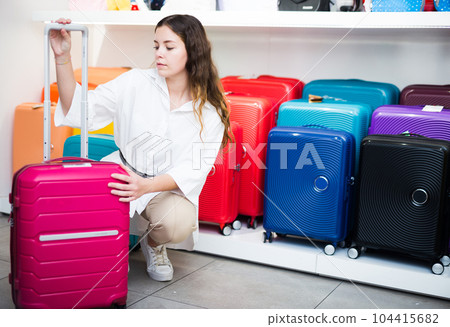 Focused girl in a shop inspects a travel suitcase 104415682