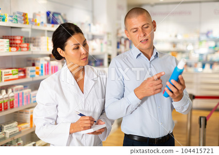 Female doctor consulting man in chemist shop 104415721