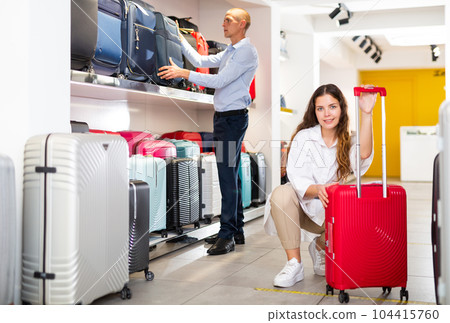 Young couple in a store chooses a travel suitcase Young couple in a store chooses a travel suitcase 104415760