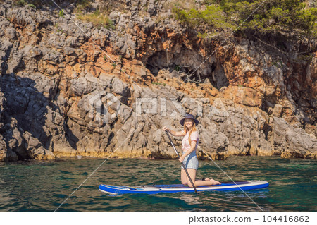 Young women Having Fun Stand Up Paddling in blue water seaamong the rocks in Montenegro. SUP Young women Having Fun Stand Up Paddling in blue water seaamong the rocks in Montenegro. SUP 104416862
