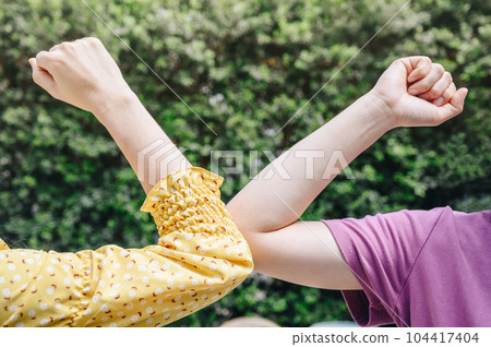 Cropped shot of two women bump elbows for greeting during coronavirus epidemic. Cropped shot of two women bump elbows for greeting during coronavirus epidemic. 104417404