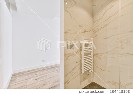 a modern bathroom with marble walls and floor to the right, there is a white towel rack on the wall 104418308