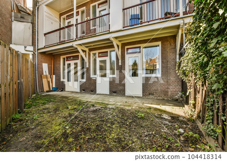 an outside view of a two story brick house with white doors and brown trim on the side of the building 104418314