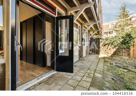 an outside view of a house with black doors and brick walkway leading up to the front door on a sunny day an outside view of a house with black doors and brick walkway leading up to the front door on a sunny day 104418316