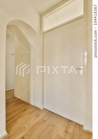 an empty room with wooden floors and white walls, there is a door leading to the left side of the room 104418367