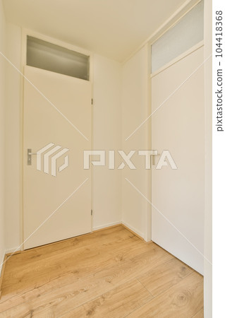 an empty room with white walls and wood flooring the door is open on the right side of the room an empty room with white walls and wood flooring the door is open on the right side of the room 104418368