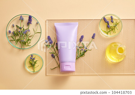 Blank label tube in purple color placed on acrylic sheet with some petri dishes and a flask of yellow liquid. Empty label for branding mockup with Lavender (Lavandula) extract Blank label tube in purple color placed on acrylic sheet with some petri dishes and a flask of yellow liquid. Empty label for branding mockup with Lavender (Lavandula) extract 104418703