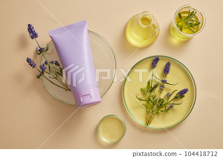 A purple tube placed on podium, displayed with laboratory glassware filled with yellow fluid and purple lavender flowers. Lavender (Lavandula) essential oil can protect your nervous system 104418712