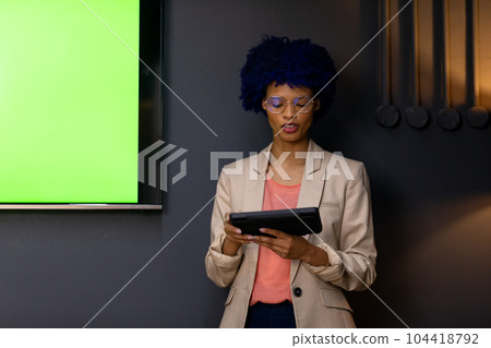 Happy biracial casual businesswoman with blue afro making presentation with tablet, copy space 104418792