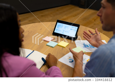 Diverse male and female colleagues in discussion using tablet in casual office meeting 104418812
