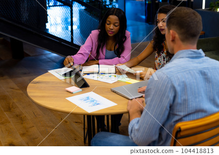 Diverse male and female colleagues in discussion using tablet in casual office meeting 104418813