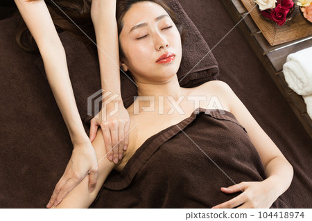The woman is receiving a massage on her upper arm. The woman is receiving a massage on her upper arm. 104418974