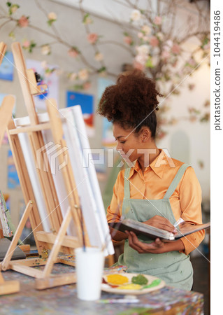 Beautiful American African artist woman painting in art studio at the university classroom Beautiful American African artist woman painting in art studio at the university classroom 104419486