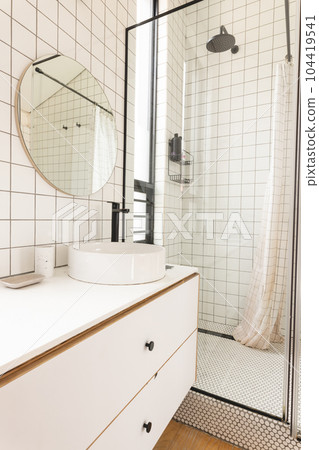 View of bright modern bathroom interior with white tiles and glass shower cabin View of bright modern bathroom interior with white tiles and glass shower cabin 104419541