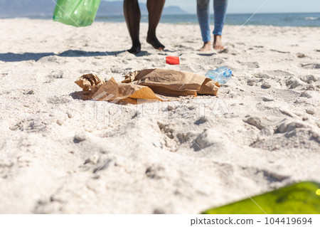 Low section of african american couple cleaning sunny beach and collecting litter, copy space 104419694