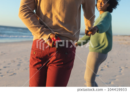 African american man holding box with ring proposing to girlfriend on sunny beach African american man holding box with ring proposing to girlfriend on sunny beach 104419933