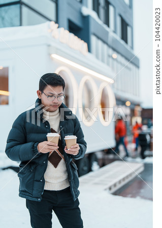 man tourist holding hot Coffee or Tea paper cup with snow in winter season during travel in Niseko. landmark and popular for attractions in Hokkaido, Japan. Travel and Vacation concepts 104420023
