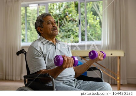 Determined senior biracial male patient in wheelchair using dumbbells Determined senior biracial male patient in wheelchair using dumbbells 104420185