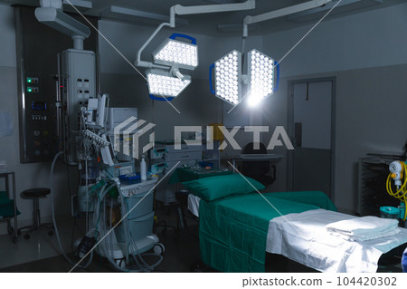 General view of operating theatre with surgical table, equipment and lamps 104420302