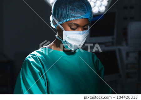 African american female surgeon wearing surgical gown and face mask in operating theatre African american female surgeon wearing surgical gown and face mask in operating theatre 104420313