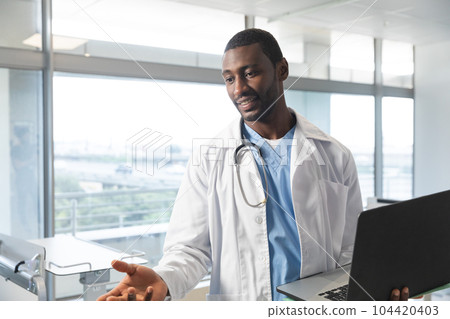 African american male doctor wearing lab coat and stethoscope, using laptop at hospital African american male doctor wearing lab coat and stethoscope, using laptop at hospital 104420403