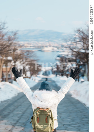 Woman tourist Visiting in Hakodate, Traveler in Sweater sightseeing Hachiman Zaka Slope with Snow in winter. landmark and popular for attractions in Hokkaido, Japan. Travel and Vacation concept Woman tourist Visiting in Hakodate, Traveler in Sweater sightseeing Hachiman Zaka Slope with Snow in winter. landmark and popular for attractions in Hokkaido, Japan. Travel and Vacation concept 104420574
