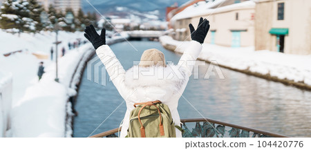 Woman tourist Visiting in Otaru, happy Traveler in Sweater sightseeing Otaru canal with Snow in winter season. landmark and popular for attractions in Hokkaido, Japan. Travel and Vacation concept Woman tourist Visiting in Otaru, happy Traveler in Sweater sightseeing Otaru canal with Snow in winter season. landmark and popular for attractions in Hokkaido, Japan. Travel and Vacation concept 104420776