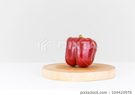Red bell peppers placed on a wooden plate. 104420976