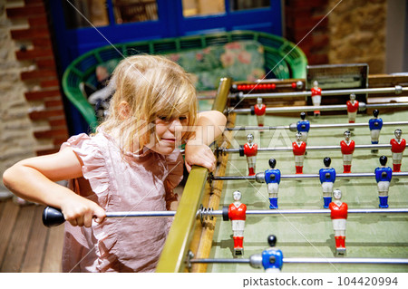 Little preschool girl playing table soccer. Happy excited child having fun with family game. Little preschool girl playing table soccer. Happy excited child having fun with family game. 104420994