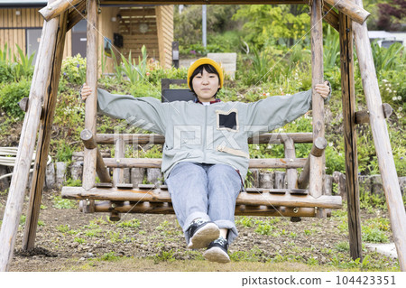 Elementary school children on a wooden swing at the campsite 104423351