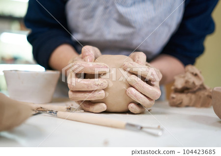 woman forming clay pot shape by hands, closeup in artistic studio woman forming clay pot shape by hands, closeup in artistic studio 104423685