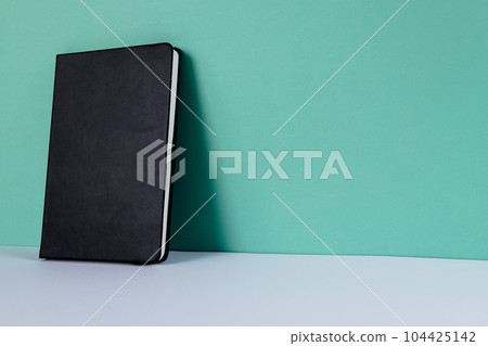 Close up of black notebook with copy space on green background Close up of black notebook with copy space on green background 104425142