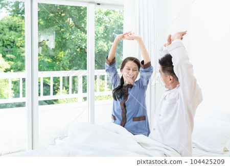 Smiling elderly couple stretching in bed in the morning 104425209