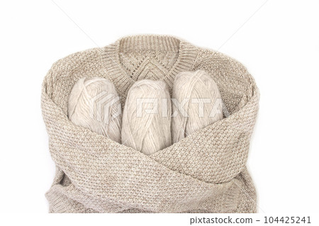 Knitted sweater hugs skeins of yarn on white isolated background. Concept of knitting, sewing. Copy space Knitted sweater hugs skeins of yarn on white isolated background. Concept of knitting, sewing. Copy space 104425241