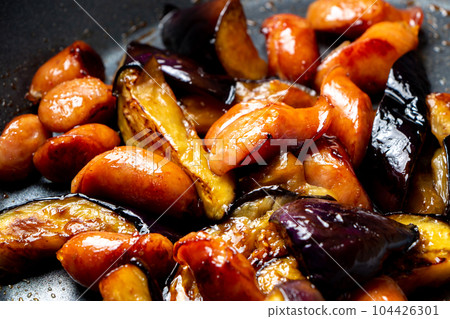 A cooking scene where eggplant and wiener sausage are fried in a frying pan. A cooking scene where eggplant and wiener sausage are fried in a frying pan. 104426301