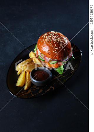 Burger with beef patty. Marbled meat.Served with potato slices. Black background.Copy space. Vertical photo. 104426675