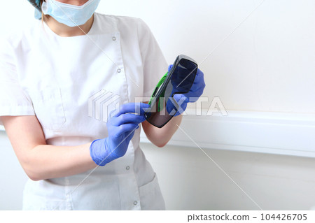 The dentist's assistant holds protective glasses in his hands. Protective glasses for patients.Dental services. White background. 104426705