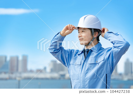 Male in work clothes, helmet, blue sky Male in work clothes, helmet, blue sky 104427238