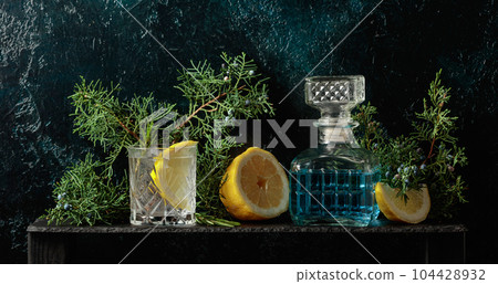 Cocktail gin-tonic with ice, lemon, and rosemary in a frozen glass. 104428932
