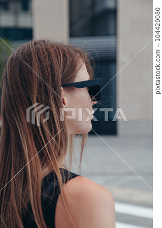 Side view photo of young woman in sunglasses outdoors in city Side view photo of young woman in sunglasses outdoors in city 104429080
