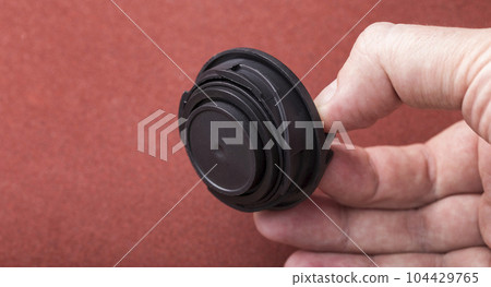 Black car oil filler cap in the mechanic's hand. Close-up 104429765