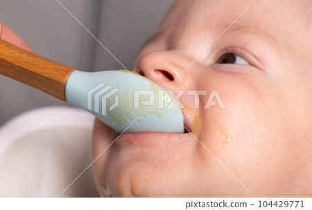 A little boy caucasian has been trying porridge and fruit puree for 6 months. Weight gain in infants, caloric content of food, close-up 104429771