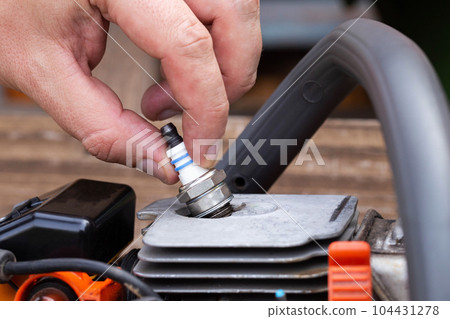 Removing the spark plug from the chainsaw cylinder. Replacing a new spark plug, a malfunction in the ignition of the fuel. Close-up 104431278