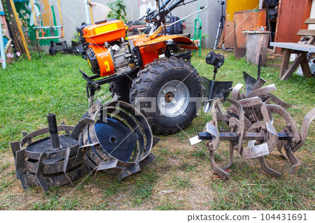 Agricultural walk-behind tractor with a set of attachments, hiller, milling cutters and lugs. Two-wheel tractor, industry Agricultural walk-behind tractor with a set of attachments, hiller, milling cutters and lugs. Two-wheel tractor, industry 104431691