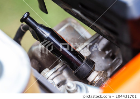 Spark plug in the engine cylinder of a walk-behind tractor. Maintenance of the ignition system. Industry Spark plug in the engine cylinder of a walk-behind tractor. Maintenance of the ignition system. Industry 104431701