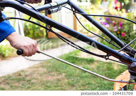 The worker adjusts the gear changes in the walk-behind tractor before running. Copy space for text, transmission The worker adjusts the gear changes in the walk-behind tractor before running. Copy space for text, transmission 104431709
