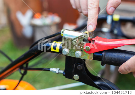 A man presses the handle of the safe shutdown of a walk-behind tractor with his hand during work. Copy space for text, running-in. 104431713